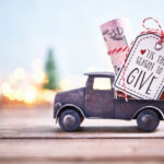 Season to Give. Truck carrying roll of dollars with holiday background